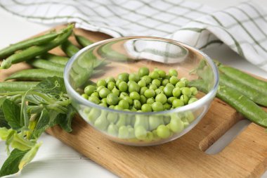 Taze taze bezelyeler beyaz ahşap masada, yakın plan.