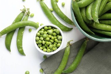 Taze taze bezelyeler beyaz ahşap masada, düz yatıyordu.