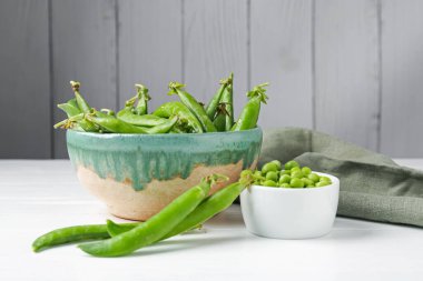 Taze taze bezelyeler beyaz ahşap masada, yakın plan.