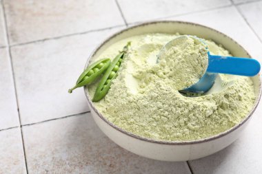 Işık döşeli masada protein tozu ve yeşil bezelyeler, yakın plan.