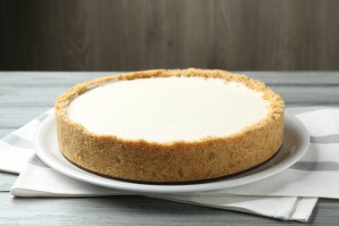 Gri ahşap masada kahverengi arka planda lezzetli bir cheesecake, yakın plan.