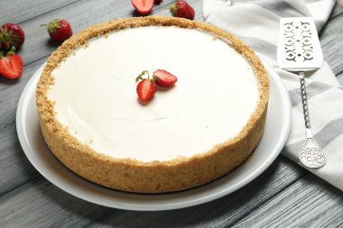 Bir lezzetli cheesecake, çilek ve sunucu gri ahşap masada, yakın plan.