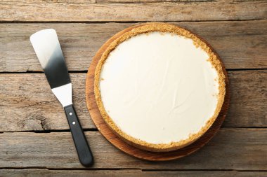 Bir lezzetli cheesecake ve sunucu ahşap masada, düz yatıyordu.