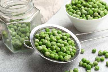 Açık gri masada taze bezelye ve turşu kavanozu, yakın plan.