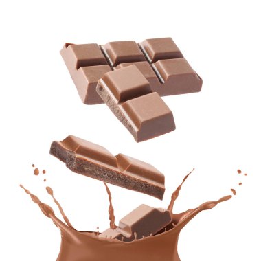 Çikolata parçaları beyaz arka plana dökülen çikolatalı sütün içine düşüyor.