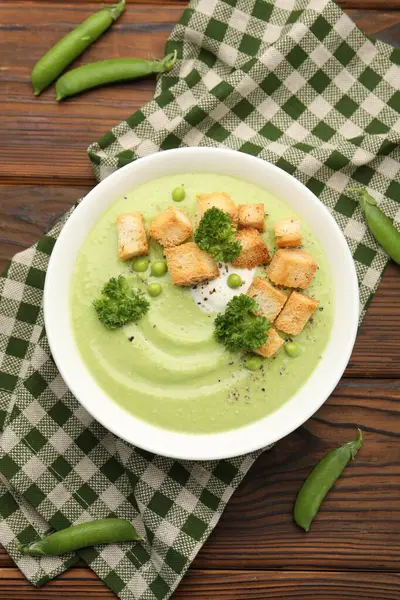 Tahta masada servis edilen kızarmış ekmek ve brokoli ile bezelye kremalı leziz çorba.