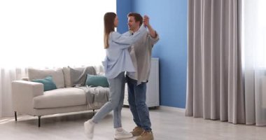 Mutlu genç çift evde dans ediyor.