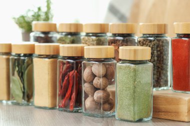 Kapalı alanda, ahşap masadaki kavanozlardaki farklı aromatik baharatlar.