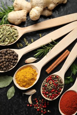 Siyah masadaki kaşıklarda bir sürü farklı baharat var.