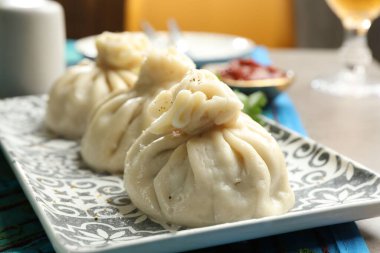 Lezzetli pişmiş khinkali gri masada servis ediliyor, yakın plan.