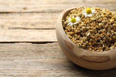 Kuru ve taze papatya çiçekleri kasede, ahşap masada, yakın plan. Metin için boşluk