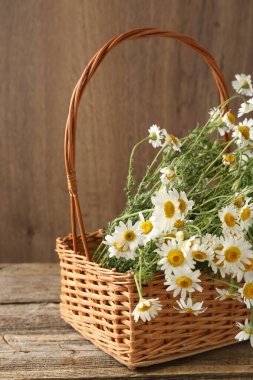 Güzel papatya çiçekleri hasır sepetin içinde ahşap masanın üzerinde, yakın plan