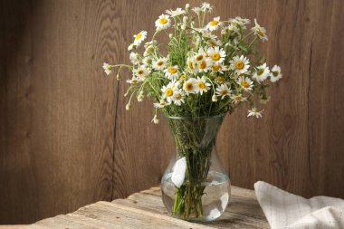 Tahta masadaki cam vazoda güzel papatya çiçekleri.