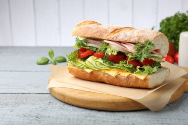 Jambonlu, peynirli ve sebzeli baget sandviç. Ahşap masa, gri arka plan, yakın plan.