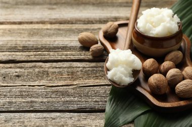 Doğal Shea yağı, fındık ve yapraklar ahşap masada, yakın plan. Metin için boşluk