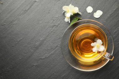 Aromatik yasemin çayı ve çiçekler gri masada, düz yerde. Metin için boşluk