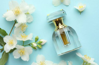 Bir şişe parfüm ve açık mavi arka planda güzel yasemin çiçekleri.