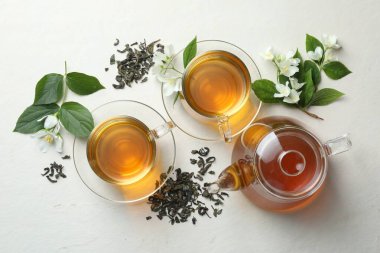 Cam fincanlarda, çiçeklerde ve yapraklarda beyaz masada yassı yasemin çayı.