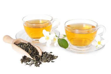 Cam fincanlarda, çiçeklerde ve kuru yapraklarda beyaz yalıtılmış yasemin çayı.