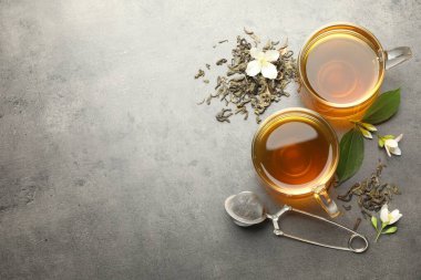 Camdan fincanlar içinde Aromatik yasemin çayı, gri masada bira ve çiçekler, düz uzanma. Metin için boşluk