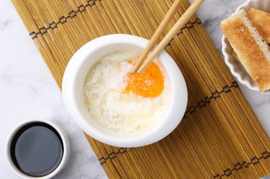 Yarısı haşlanmış yumurta, soya sosu, yemek çubukları ve beyaz mermer masada kızarmış ekmek, düz yatak. Geleneksel Asya kahvaltısı