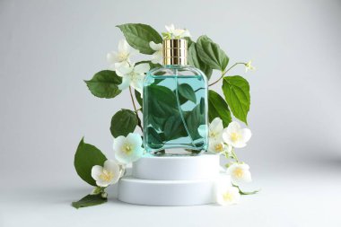 Bir şişe parfüm ve arka planda yasemin çiçekleri
