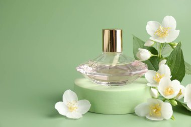 Yeşil arka planda bir şişe parfüm ve yasemin çiçeği, yakın plan. Metin için boşluk