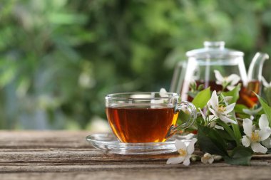 Lezzetli yasemin çayı fincanda, çaydanlık ve çiçekler ahşap masada, yakın plan. Metin için boşluk