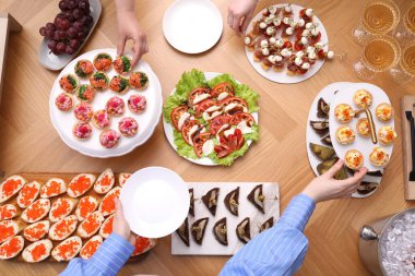 Açık büfe menüsü. İnsanlar ahşap masadan lezzetli aperatifler alıyor.