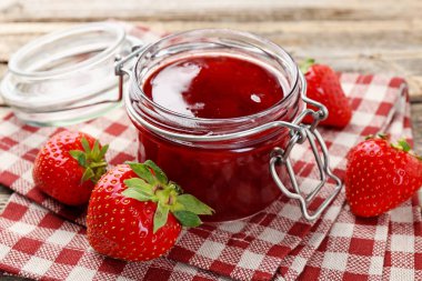 Cam kavanozda lezzetli çilek reçeli ve masada taze böğürtlen, yakın plan.