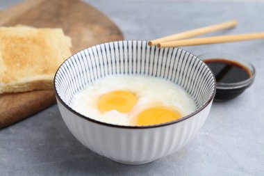 Kavanozda yarı haşlanmış yumurta, soya sosu, ekmek ve çubuklarla geleneksel Asya kahvaltısı, yakın plan.