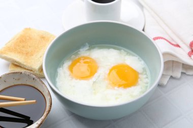 Kavanozda yarı haşlanmış yumurta, soya sosu, ekmek, yemek çubuğu ve beyaz fayanslı masada kahve ile geleneksel Asya kahvaltısı.