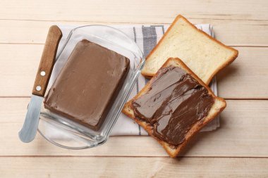 Lezzetli çikolatalı tereyağı kalecide, ekmek ve bıçak dilimleri açık ahşap masada, yukarıda.