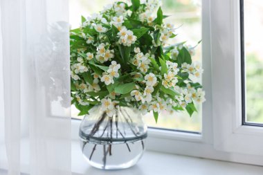 Güzel yasemin çiçekleri pencerenin yanındaki vazoda.