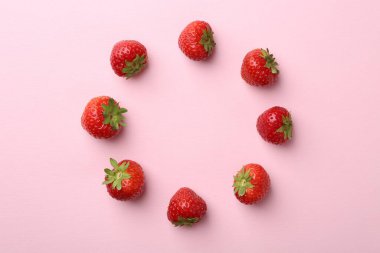 Açık pembe arka planda taze olgun çilek çerçevesi, düz. Metin için boşluk