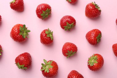 Açık pembe arka planda taze olgun çilekler, düz uzanmış.