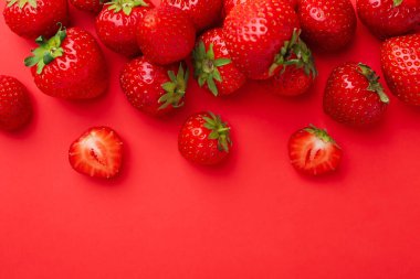 Kırmızı arka planda taze olgun çilekler, düz uzanmış. Metin için boşluk