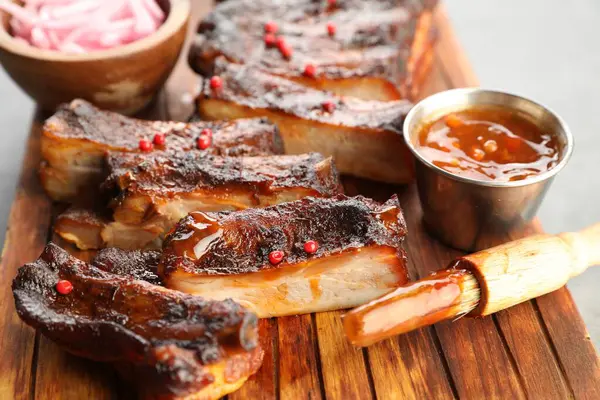 Lezzetli domuz pirzolası, sos ve fırça gri masada, yakın plan.