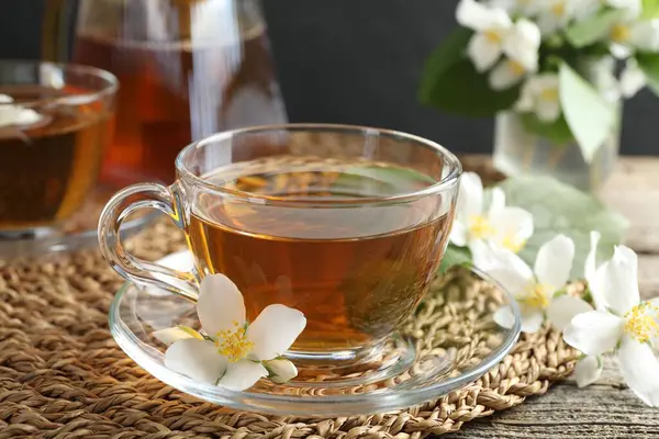 Cam bardakta yasemin çayı ve ahşap masada çiçekler, yakın plan.