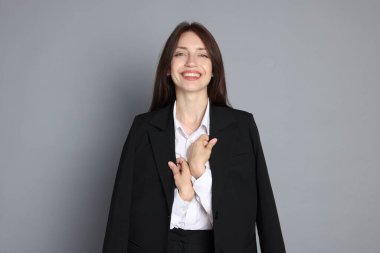 Gri arka planda takım elbiseli mutlu kadın