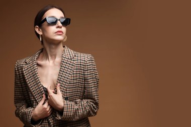 Kahverengi arka planda şık giyinmiş güzel bir kadının portresi.