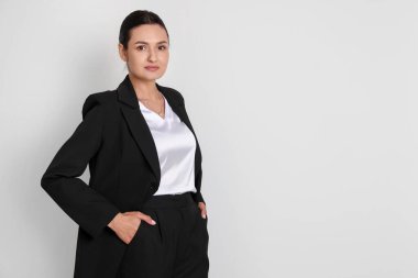Hafif arka planda takım elbiseli kendine güvenen bir iş kadını. Metin için boşluk