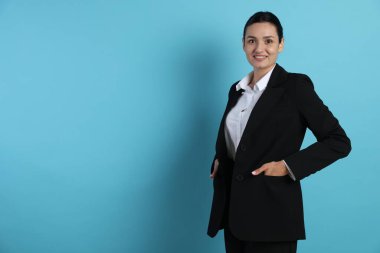 Açık mavi arka planda takım elbiseli kendine güvenen bir iş kadını. Metin için boşluk