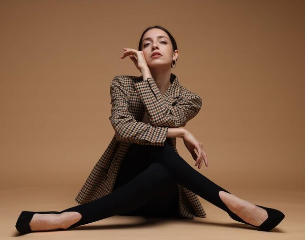 Полнометражный портрет красивой женщины в стильном наряде на бежевом фоне