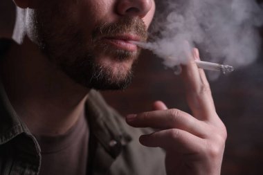 Arka planda sigara içen adam, yakın plan.