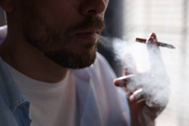 Arka planda sigara içen adam, yakın plan.