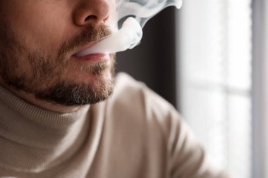 Arka planda sigara içen adam, yakın plan.