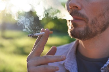 Arka planda sigara içen adam, yakın plan.