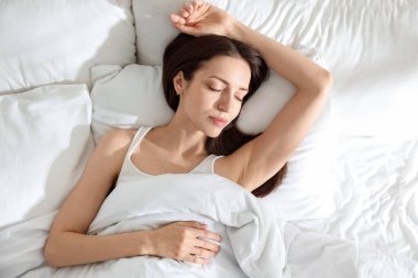 Evdeki yumuşak yataklı, üst manzaralı yatakta yatan kadın.