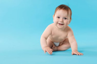 Açık mavi arka planda emekleyen şirin bir bebek. Metin için boşluk